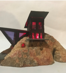 A sculpture of a black structure on a mountain