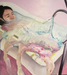 A person sitting in a bathtub full of newspaper articles