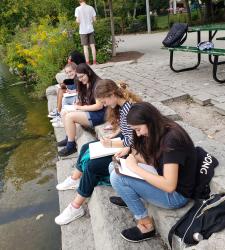 Students drawing in sketchbooks at a pond