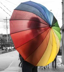 A black-and-white image of a person holding a coloured umbrella